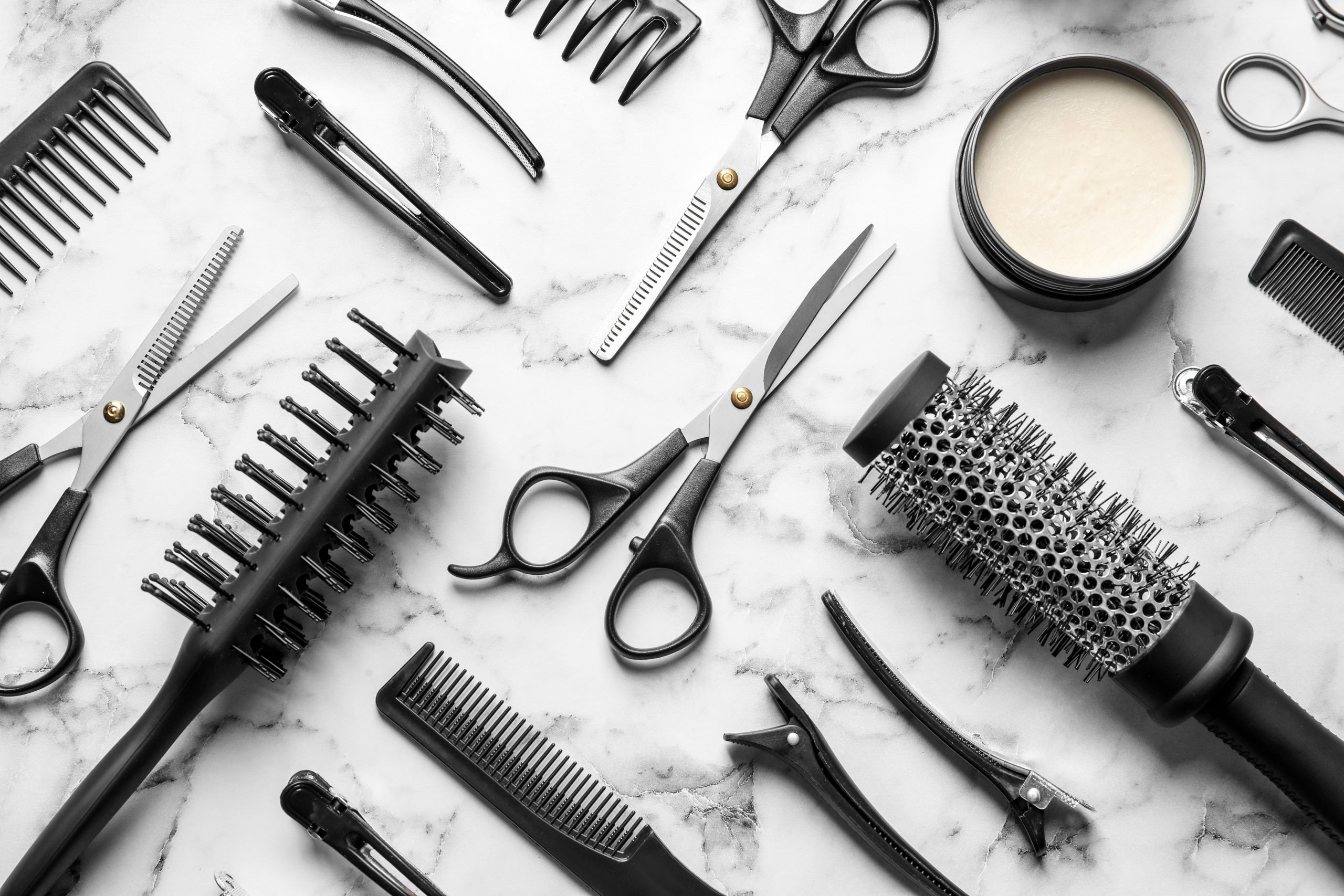 Flat lay composition with scissors and other hairdresser's accessories on white marble background